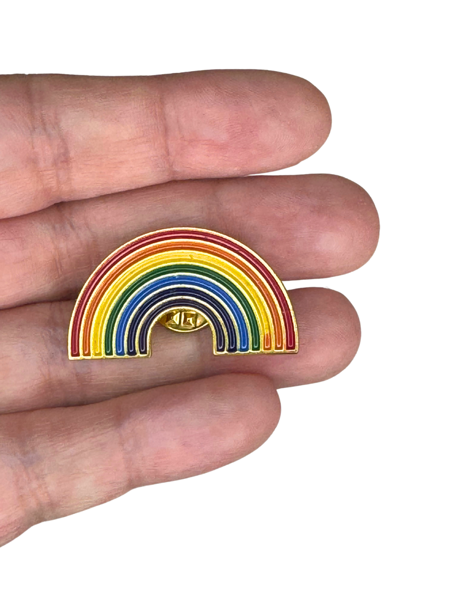 Rainbow enamel pin held between fingers for scale