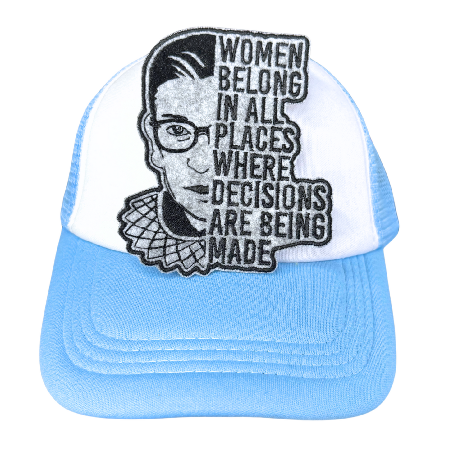 "Blue and white trucker hat with an embroidered RBG patch that reads 'Women belong in all places where decisions are being made.'"