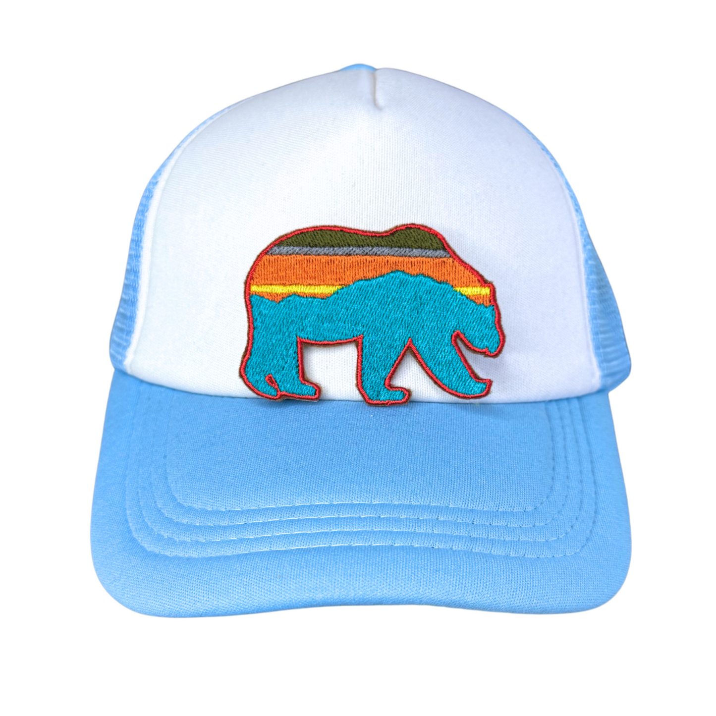 "Blue and white trucker hat featuring an embroidered Southwest-style bear patch with a colorful sunset mountain design."