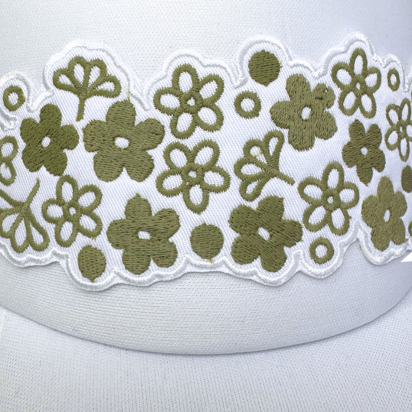 Closeup of embroidered olive green floral design inspired by vintage Pyrex on white foam trucker hat