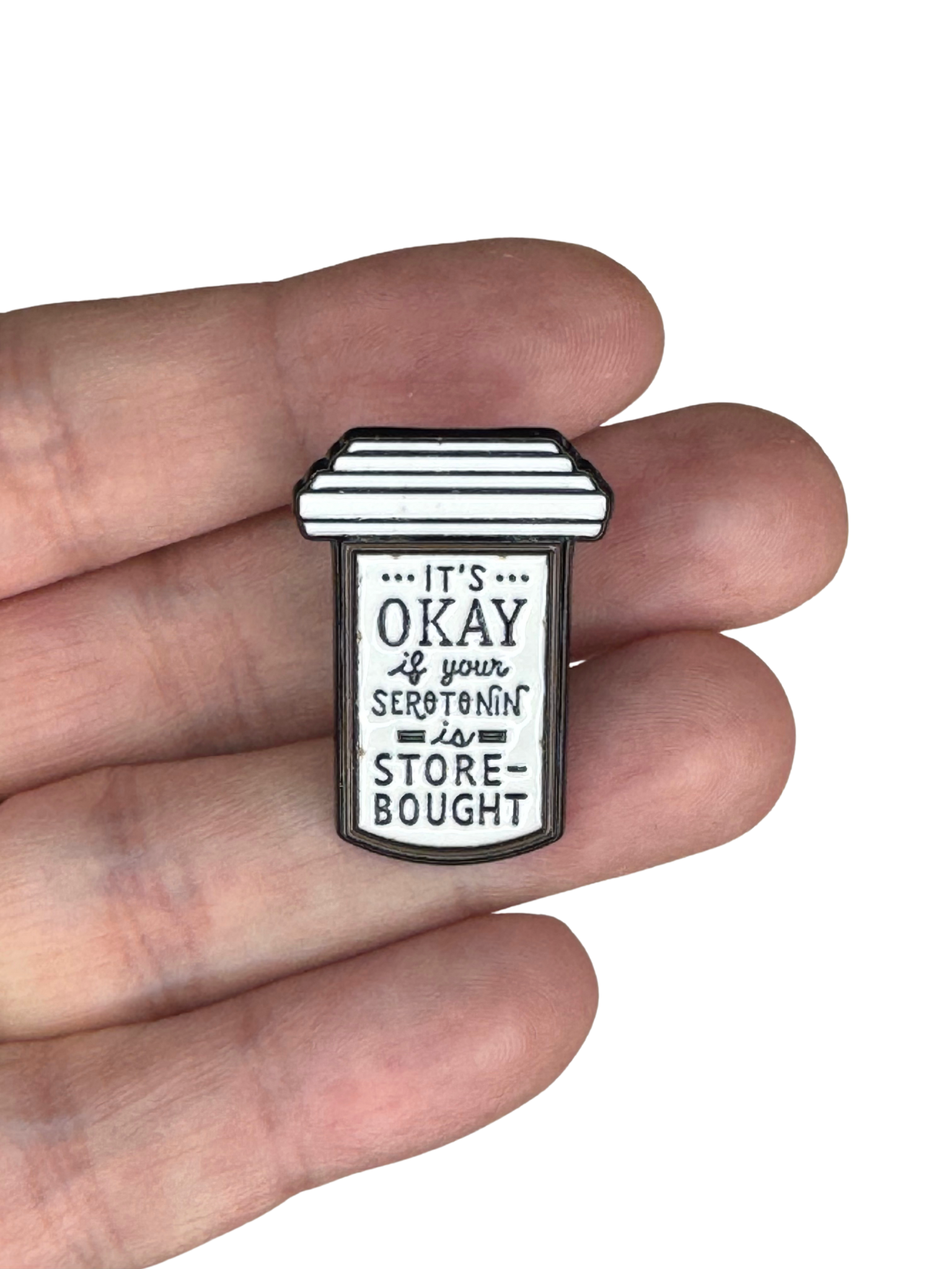 Enamel pin held in hand for scale