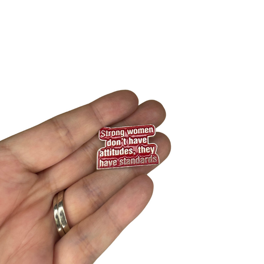 Red enamel pin in palm of a hand to show size