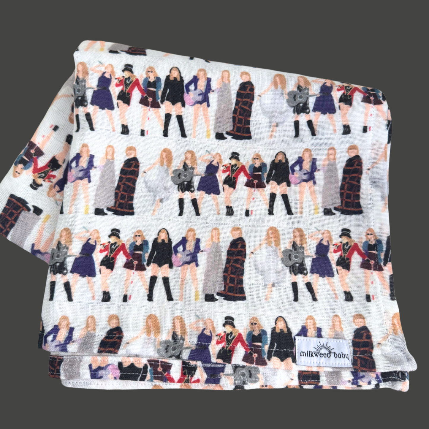 Taylor Swift-inspired baby swaddle blanket displayed on a dark background, featuring a repeating design of tour outfits from different eras. Made of soft, organic Sweet Pea Gauze.