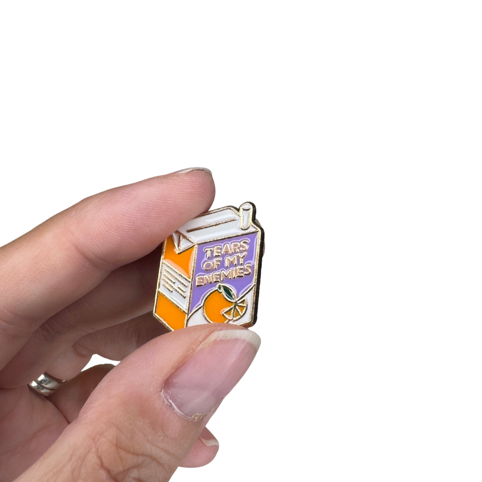Scale image showing enamel pin held between fingers for size reference