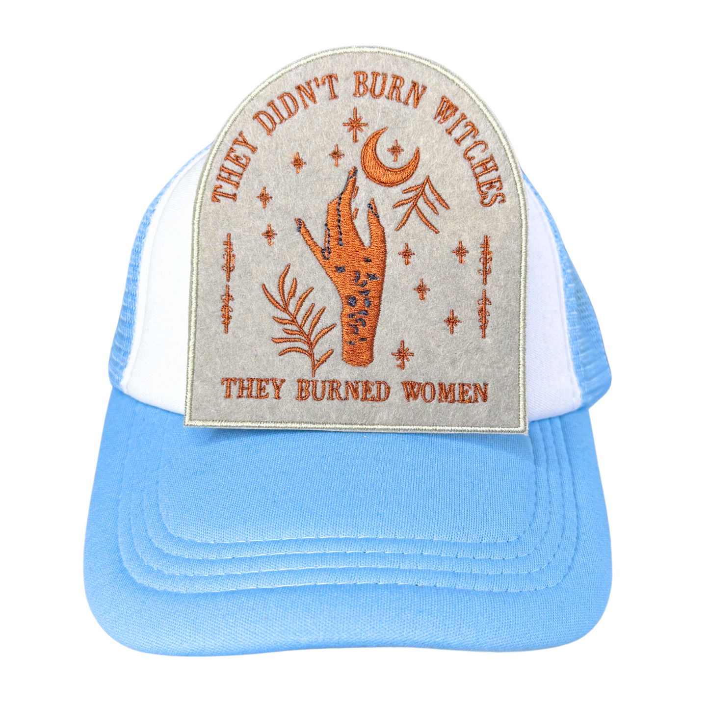 Embroidered "They Didn’t Burn Witches" patch attached to a blue and white trucker hat.