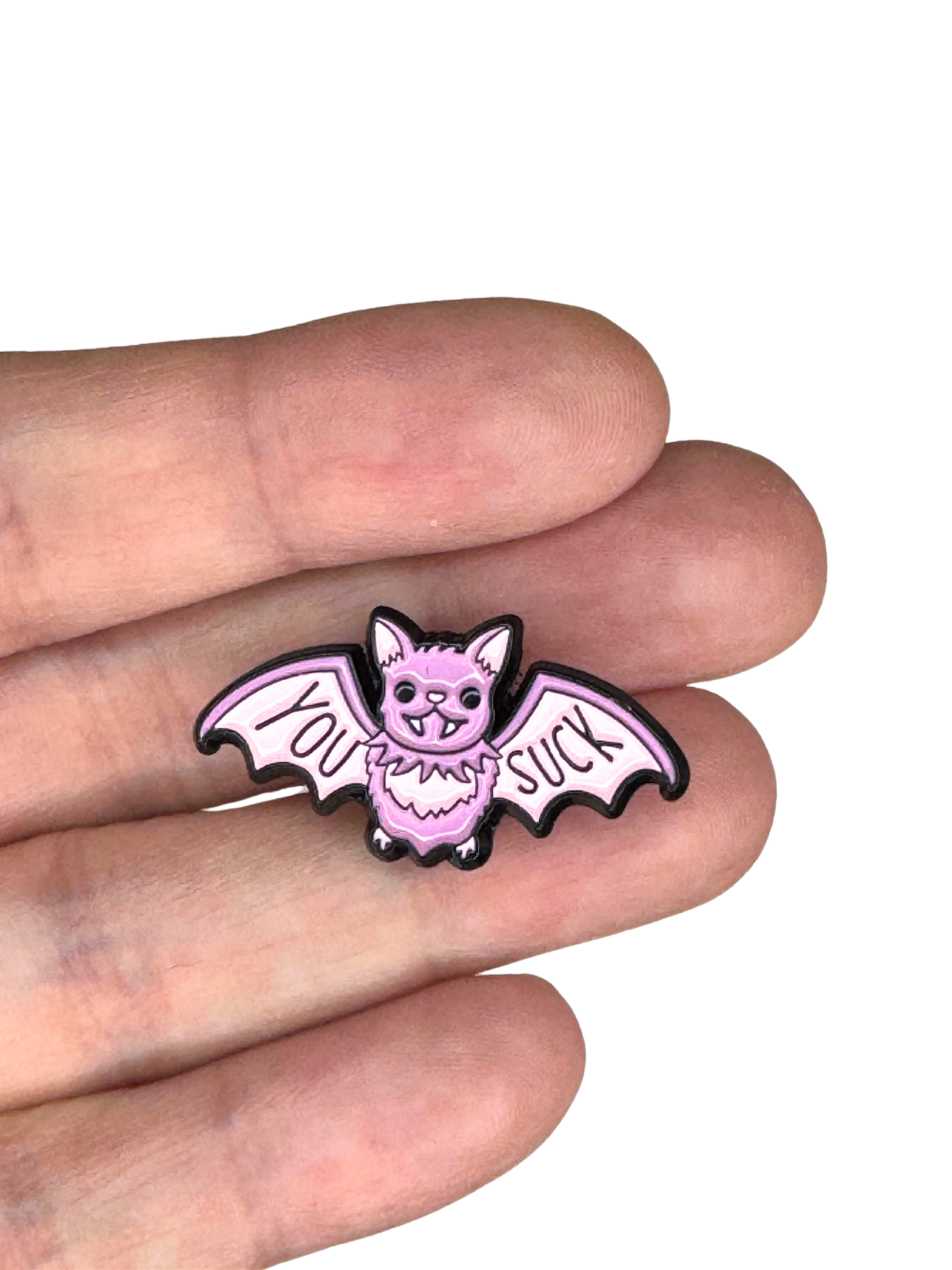 Close-up scale shot of the “You Suck” bat enamel pin held between fingers