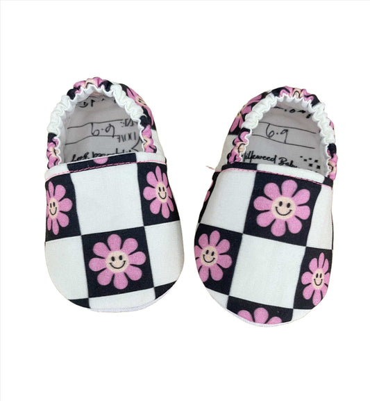 Smiley Flower Checkerboard Moccasins for babies, featuring pink flowers on a black and white checkered pattern.