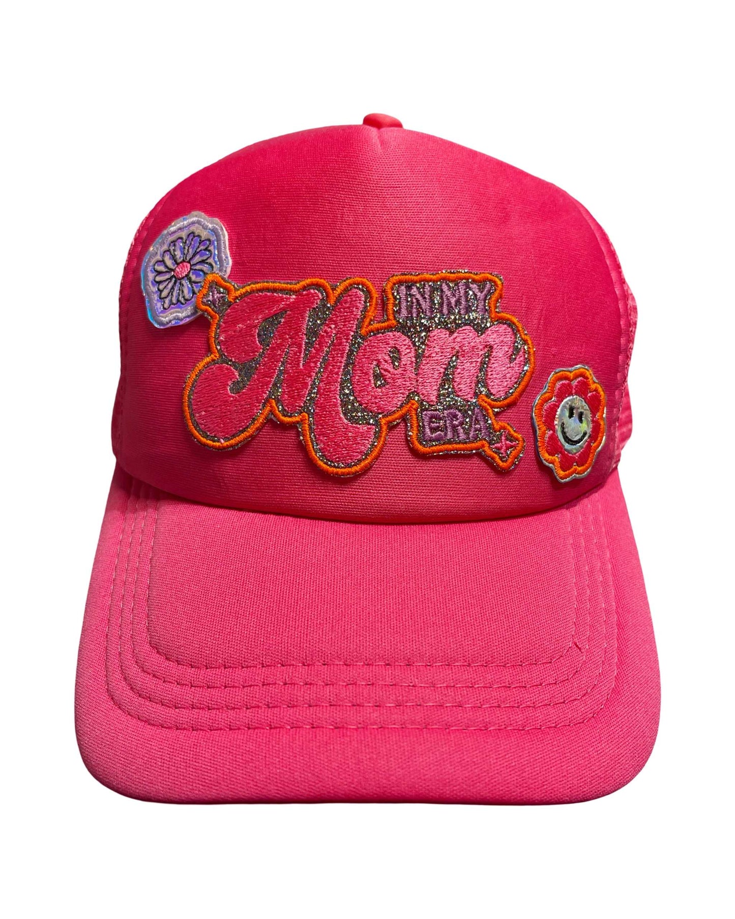 Hot pink trucker hat with 'In My Mom Era' patch and holographic flower accents.