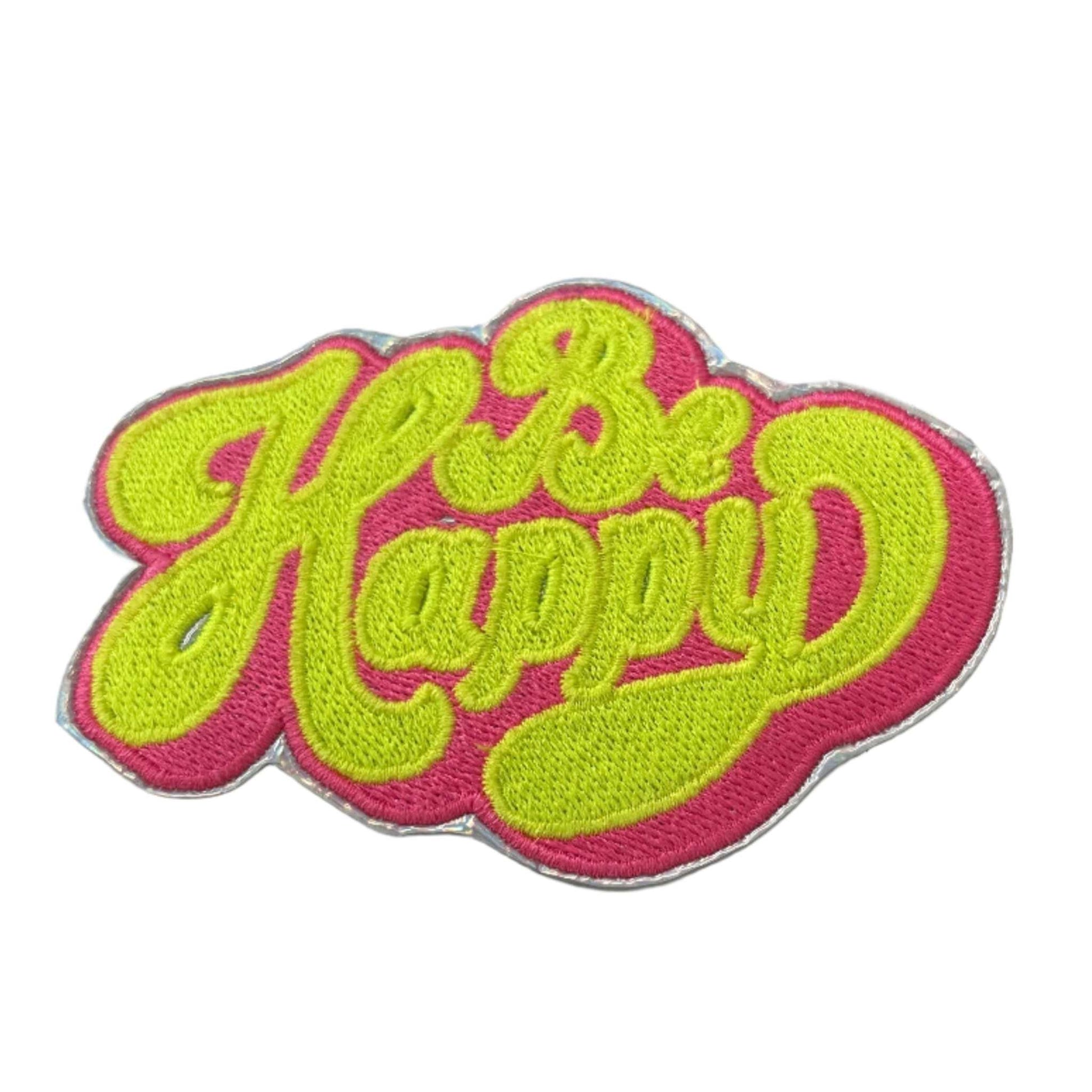 Handmade Be Happy iron-on patch with neon yellow text on neon pink and holographic silver backdrop.