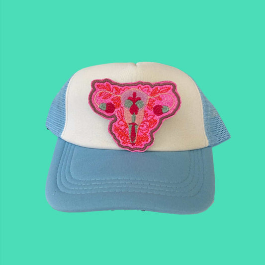 Iron-on patch featuring a vibrant depiction of a uterus with floral and botanical motifs in shades of pink and red, outlined in neon pink.