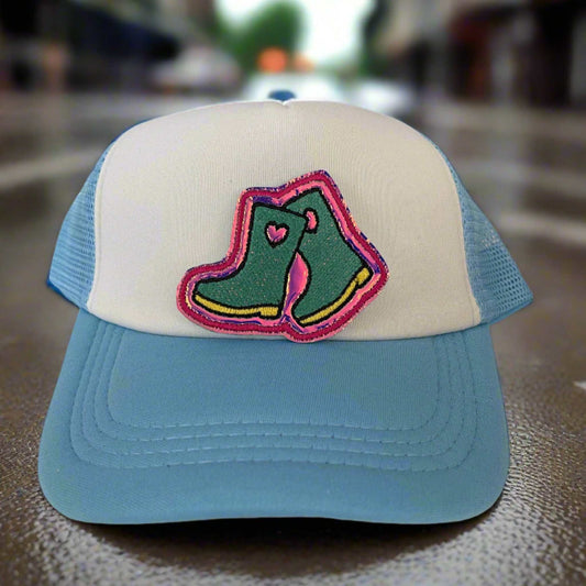 Close-up of a quirky rain boots embroidered patch with green and pink detailing, perfect for customizing hats and other accessories.