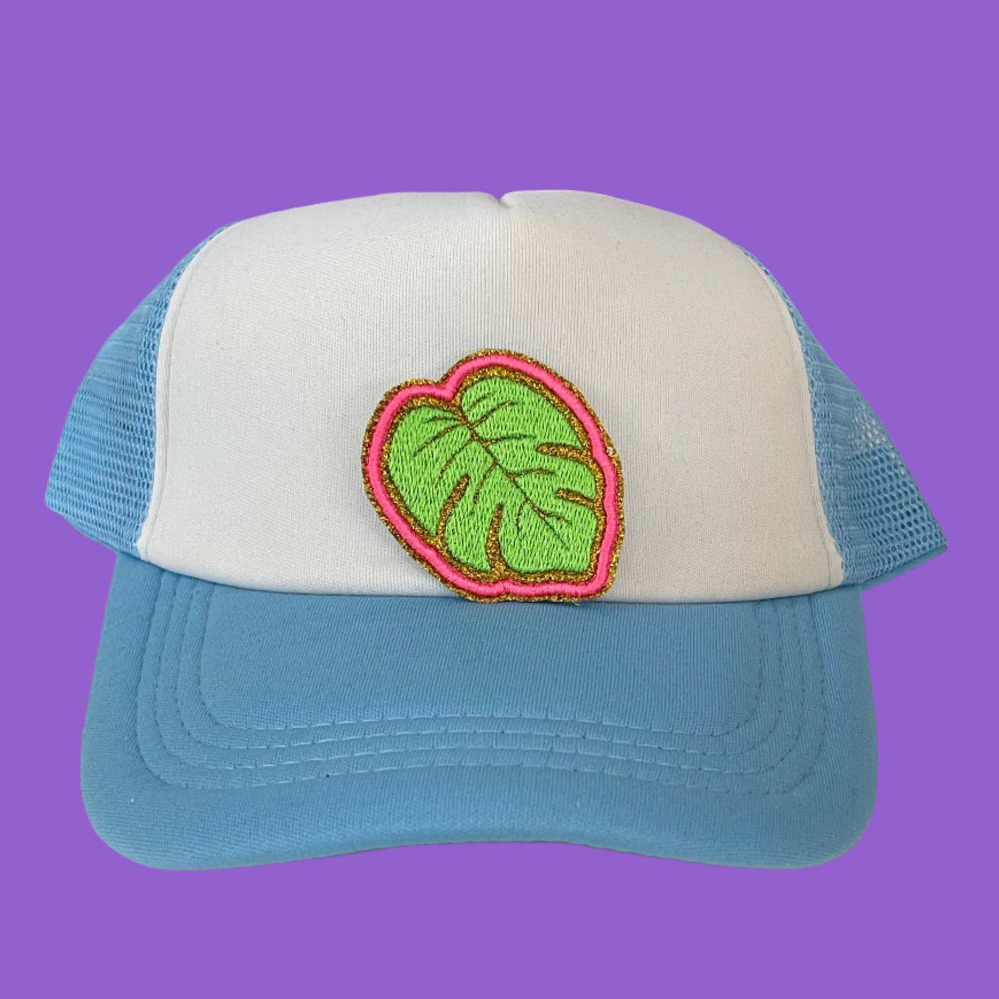 Close-up of a bright Monstera Leaf embroidered patch with green and pink detailing, ideal for customizing hats and other accessories.