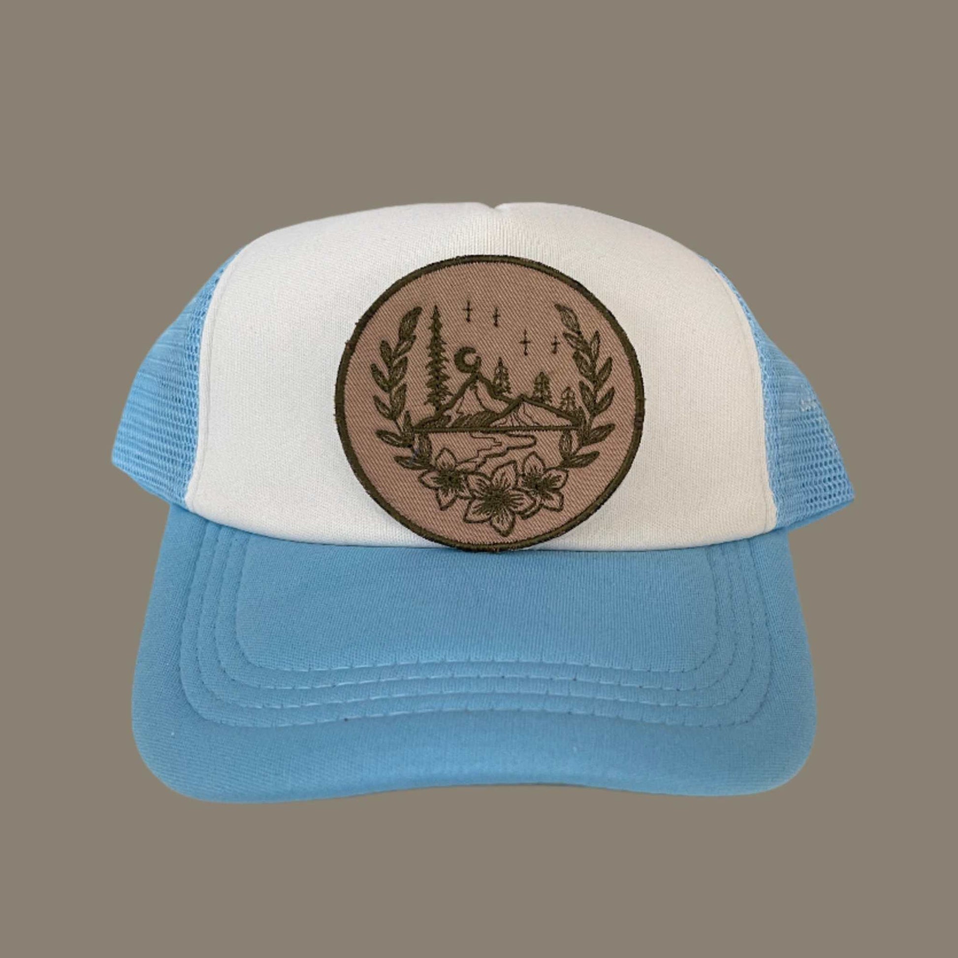 Mountain scene embroidered patch featuring a rustic design with mountains, trees, and a floral border, perfect for customizing clothing and accessories.