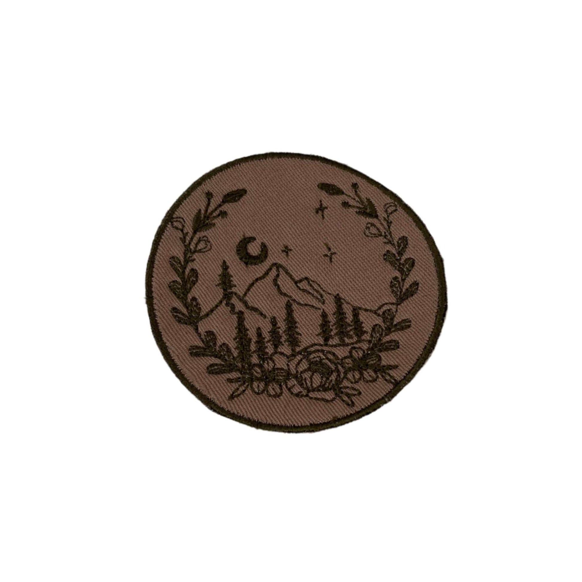 Mountain scene embroidered patch with rustic design, featuring mountains, trees, and floral border.
