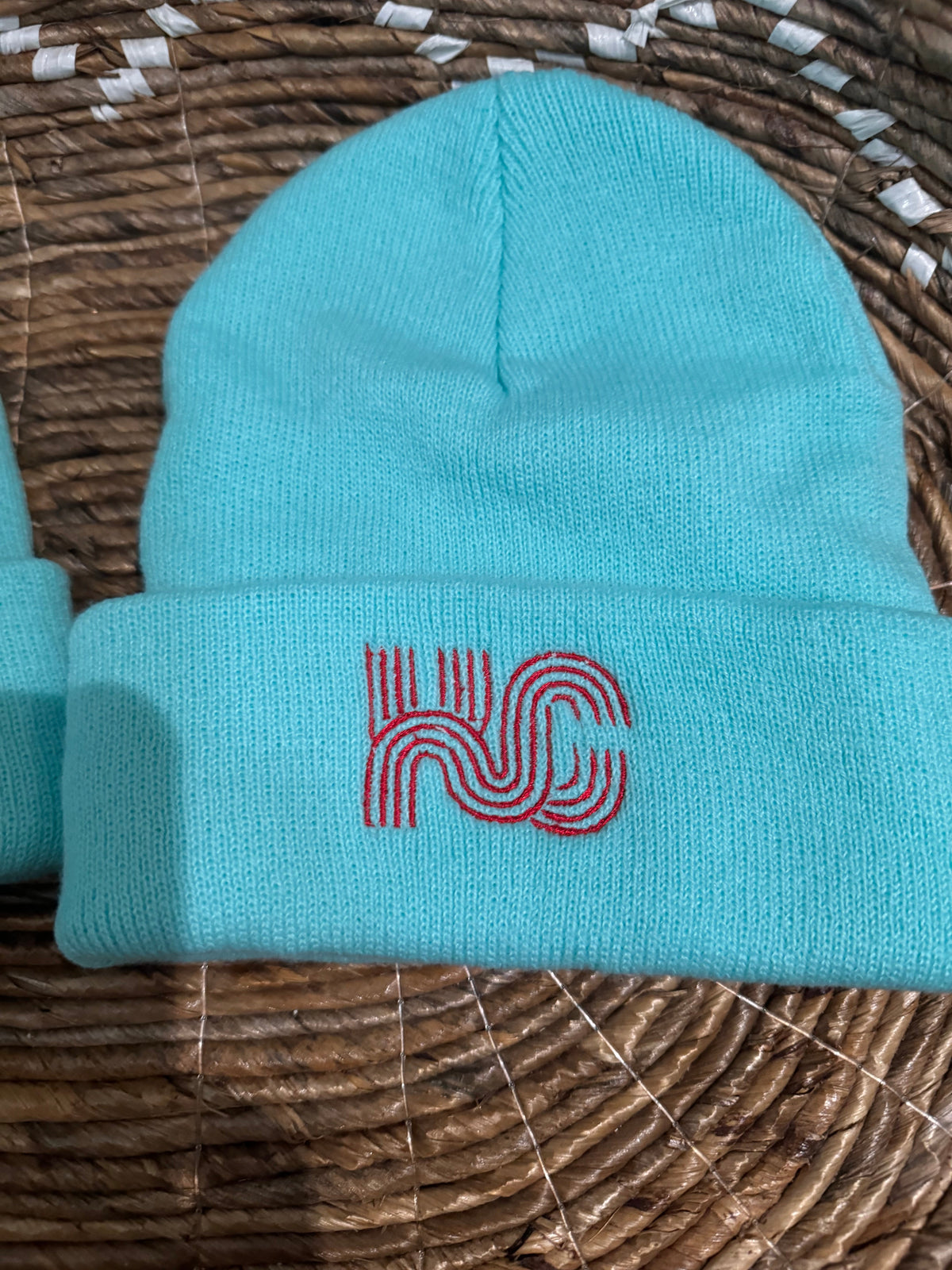 KC logo embroidered beanie, red on teal background.