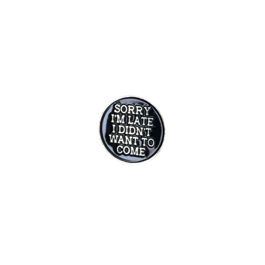 Black and white enamel pin that says “Sorry I’m Late I Didn’t Want to Come” on plain background