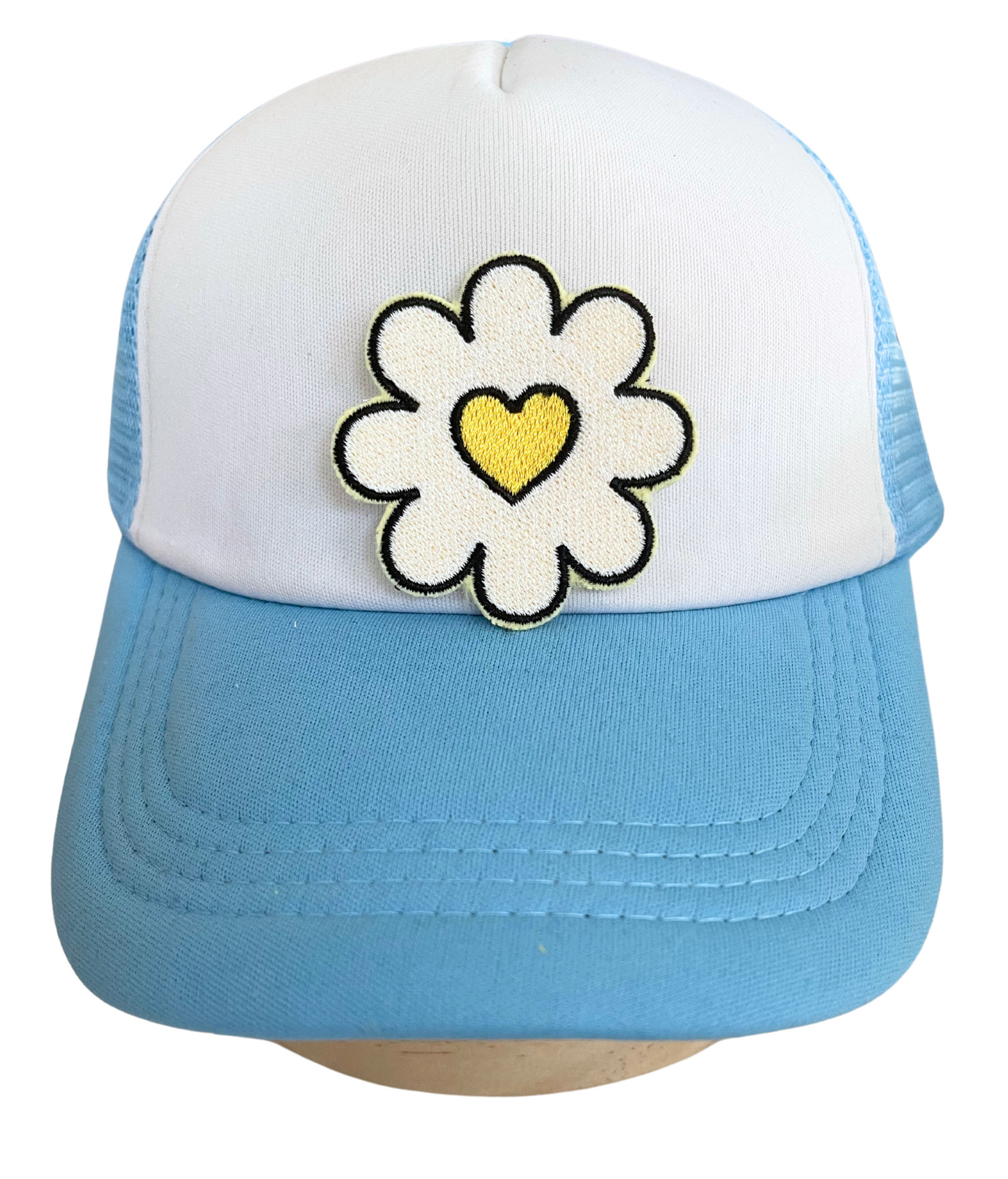 Handmade daisy patch with a yellow heart center, embroidered on fabric.