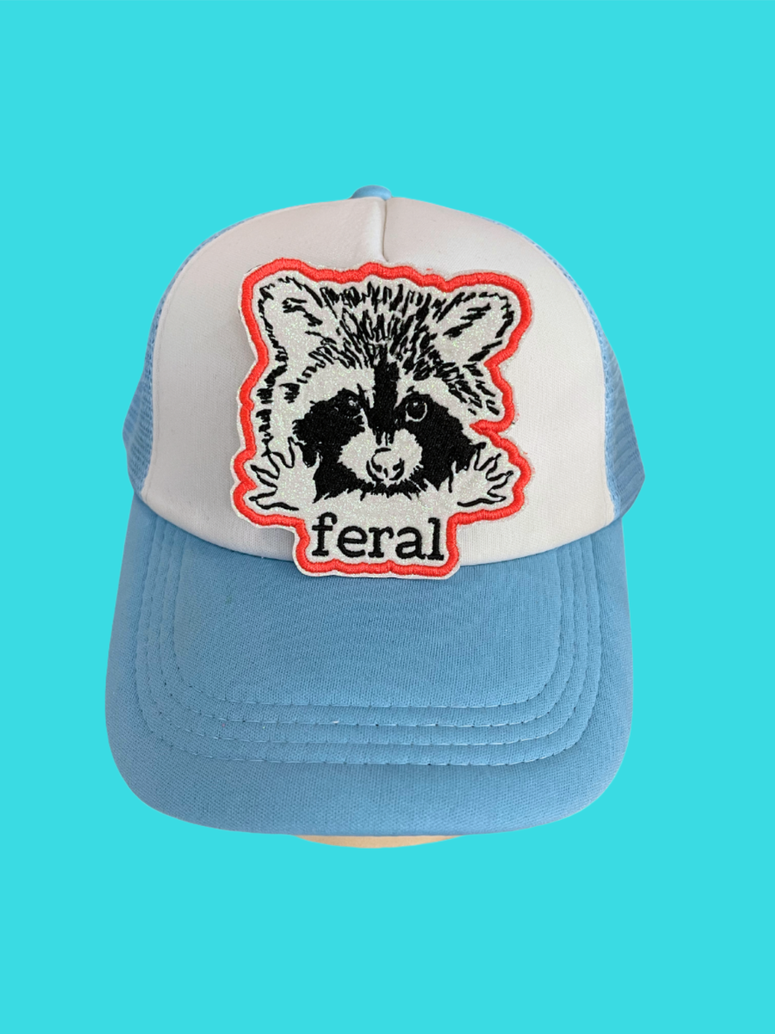 Custom embroidered patch featuring a raccoon with the word "feral," perfect for personalizing hats and apparel.