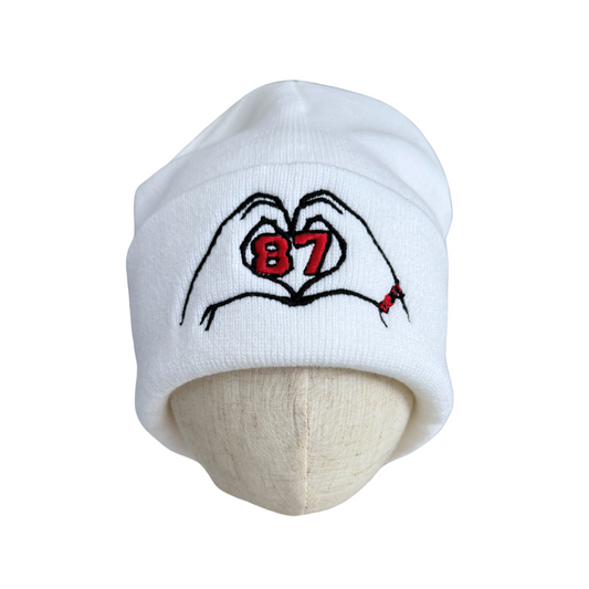 White beanie with heart-shaped hands and "87" tribute to Travis Kelce and Taylor Swift, adult size.