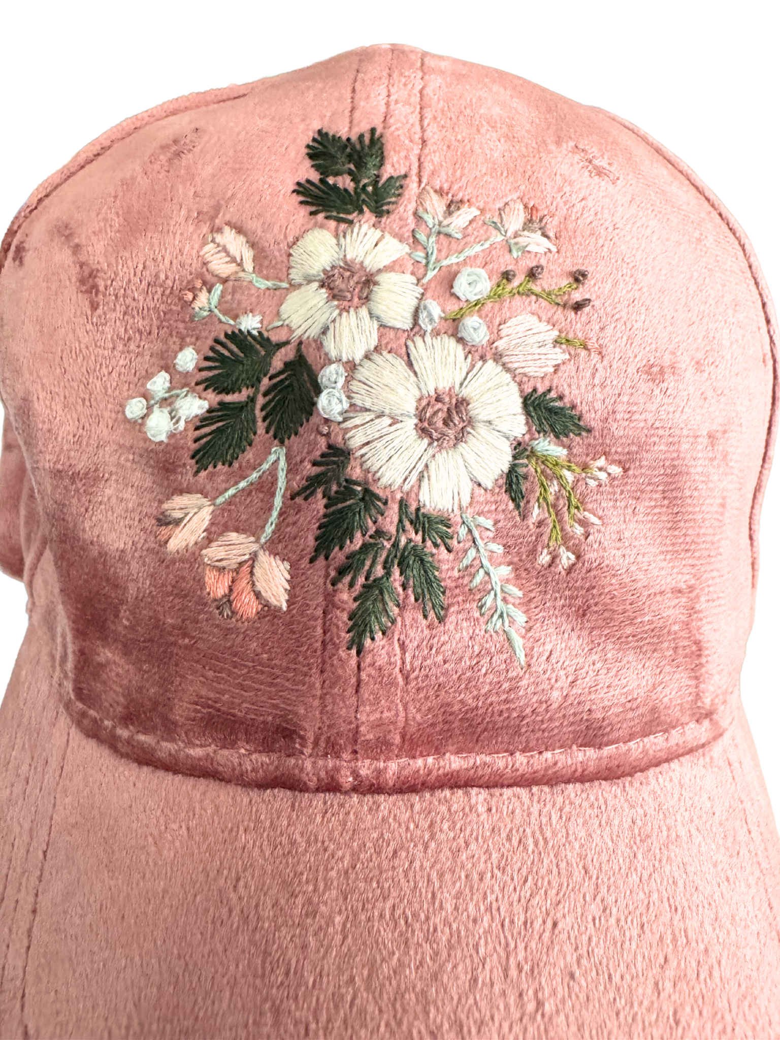Hand-embroidered floral design on a blush pink velvet hat with white and blush flowers.

