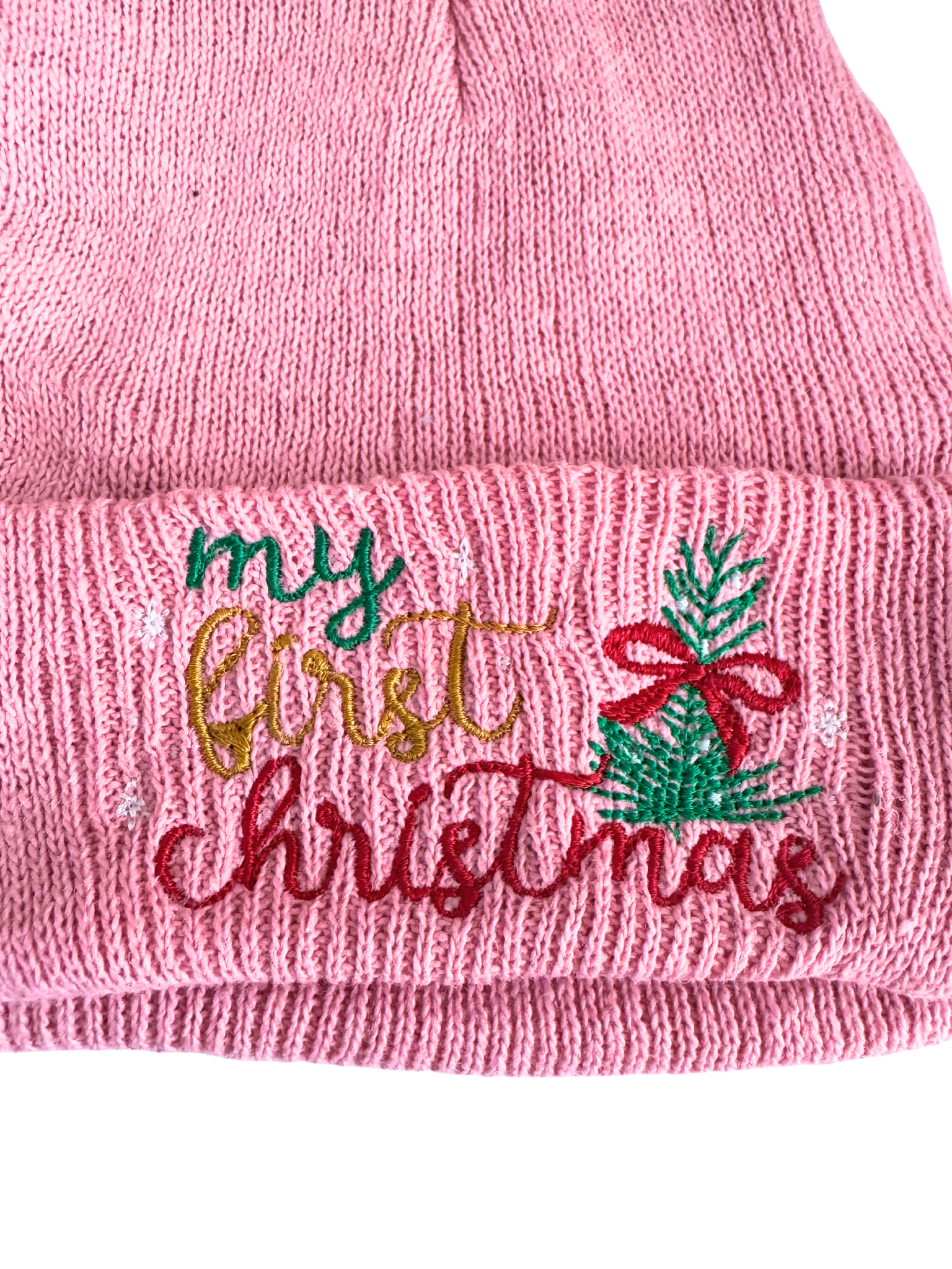 Pink beanie with "My First Christmas" embroidery, featuring a Christmas tree with a red bow and festive lettering for baby wear.

