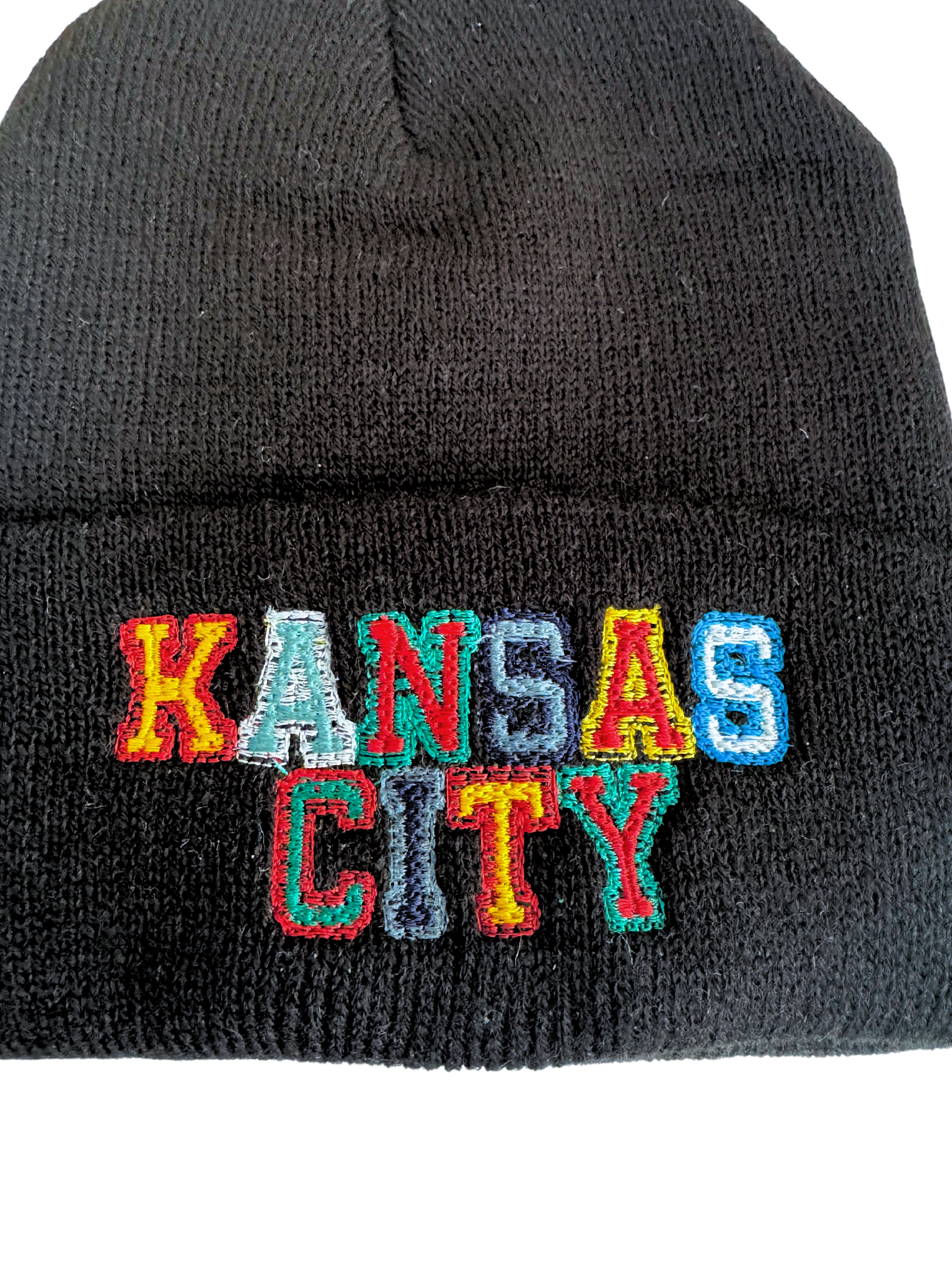 Black knit beanie with "Kansas City" embroidered in multicolored lettering representing KC sports teams.

