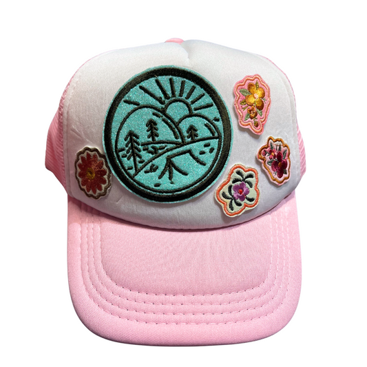 Kids' pink and white trucker hat with camping and floral patches.