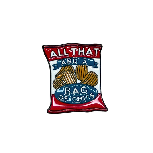 A red, white, and blue enamel pin shaped like a bag of chips that says "All That and a Bag of Chips."

