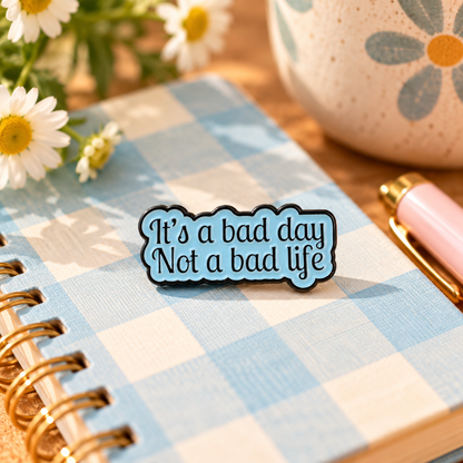 It's a Bad Day Not a Bad Life blue enamel pin in a styled editorial scene