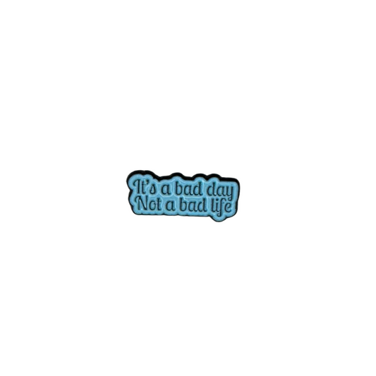 Enamel pin reading “It’s a bad day, not a bad life” in blue text on white background

