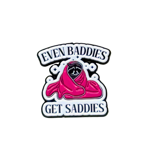 Enamel pin shaped like a cloaked sad girl with text “Even Baddies Get Saddies” on a white background.
