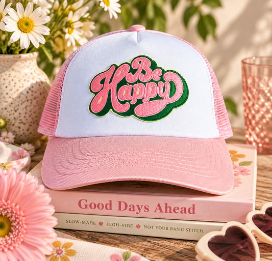 Pink and white Be Happy trucker hat styled with flowers and cheerful accessories