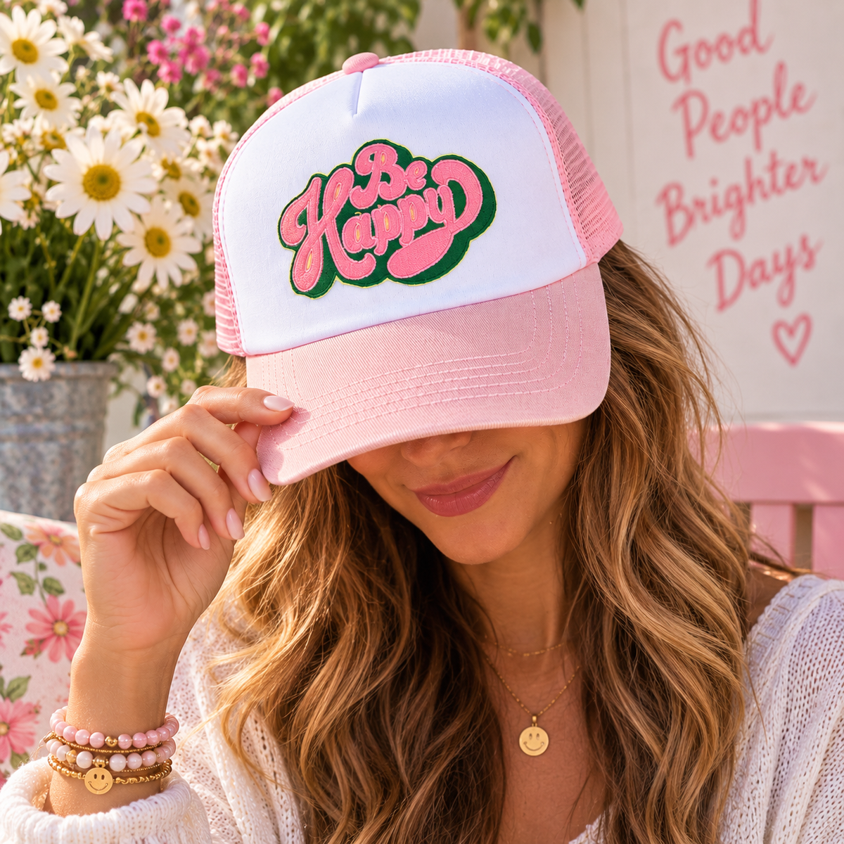 Model wearing the pink and white Be Happy trucker hat