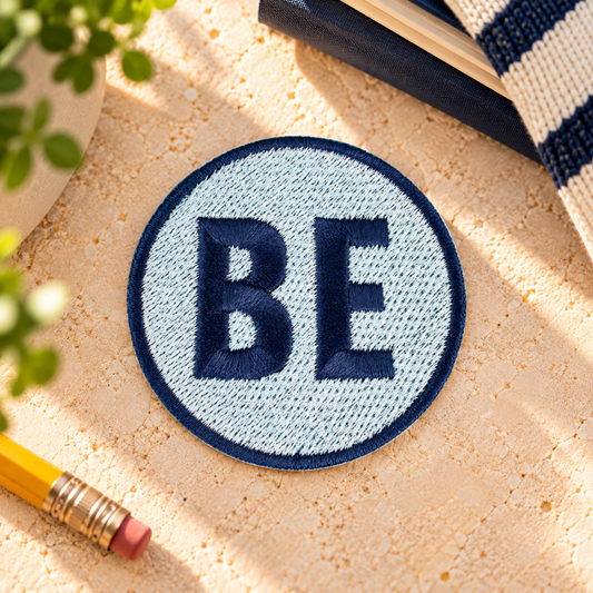 Belinder Elementary navy and white BE embroidered iron-on patch styled on warm stone