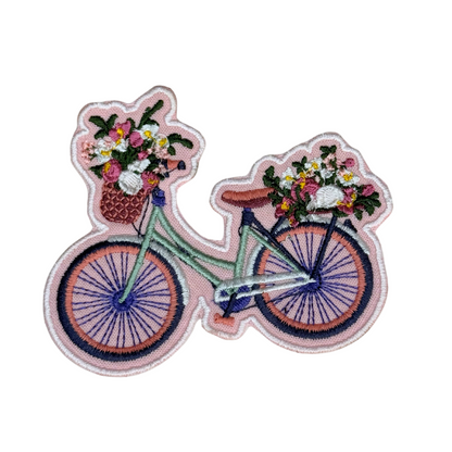 Flat lay of embroidered bicycle with flowers patch on white background
