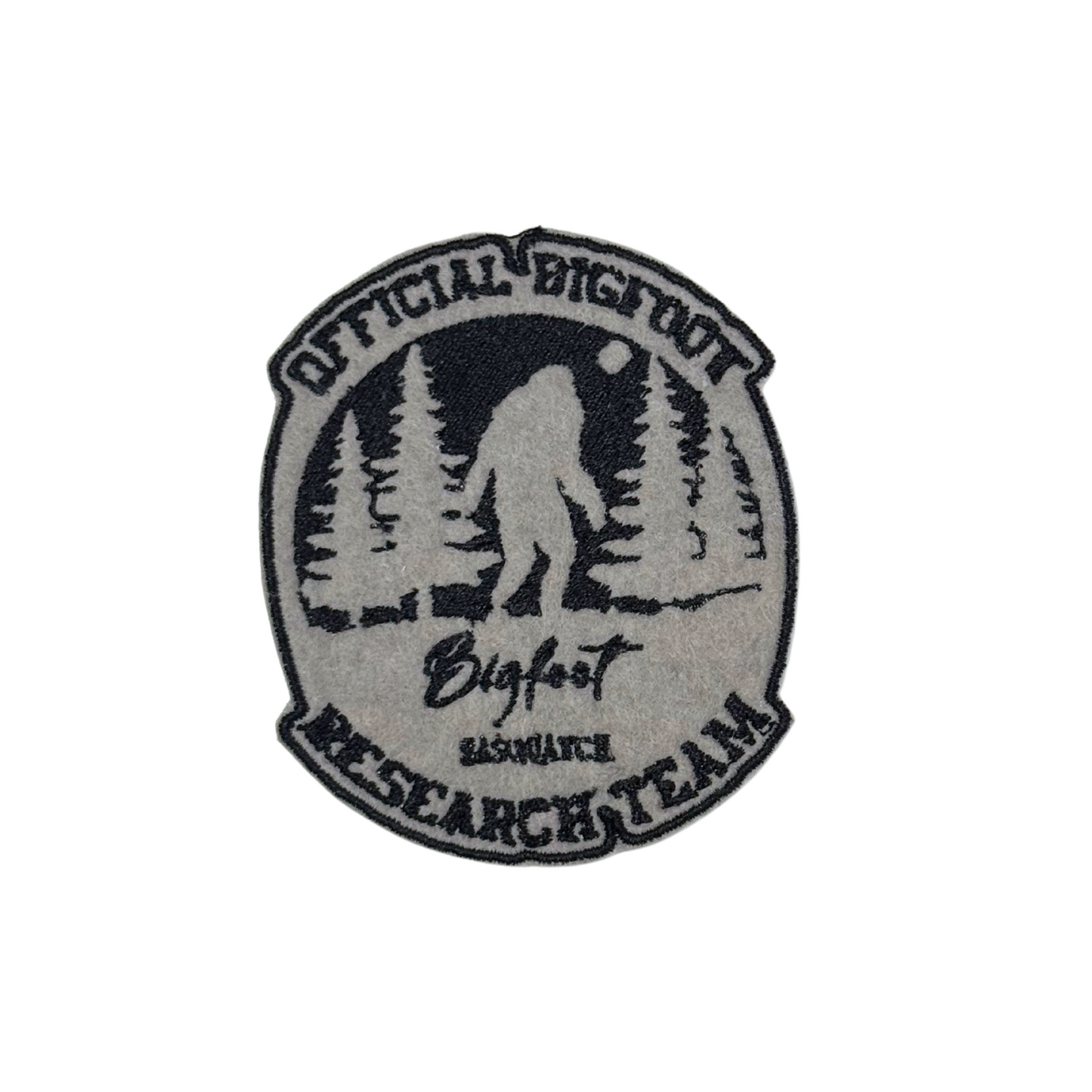 Close-up of an embroidered "Official Bigfoot Research Team" patch featuring Sasquatch walking in the forest.
