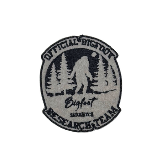 Close-up of an embroidered "Official Bigfoot Research Team" patch featuring Sasquatch walking in the forest.
