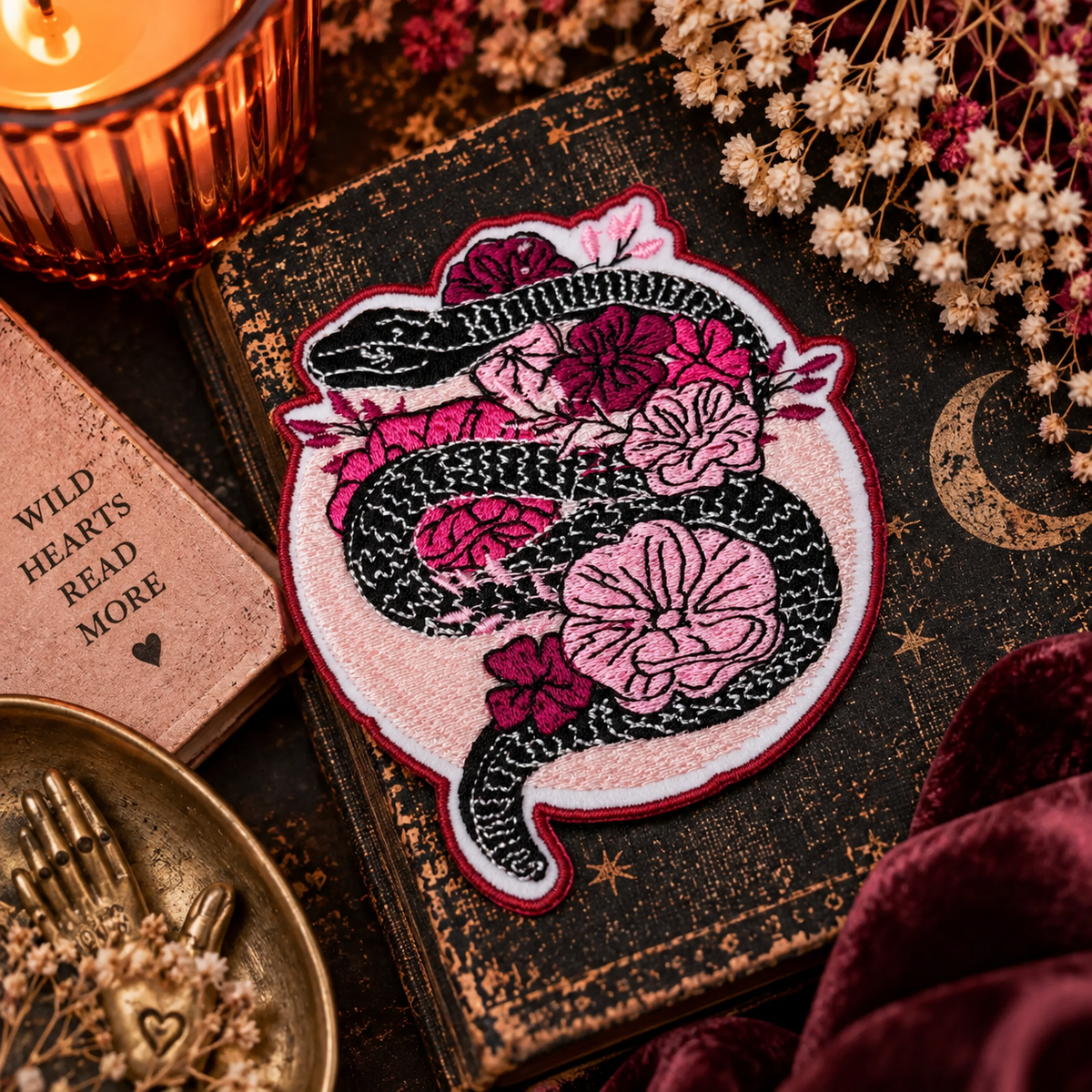 Black snake and pink flowers embroidered iron-on patch styled in a warm boho flat lay
