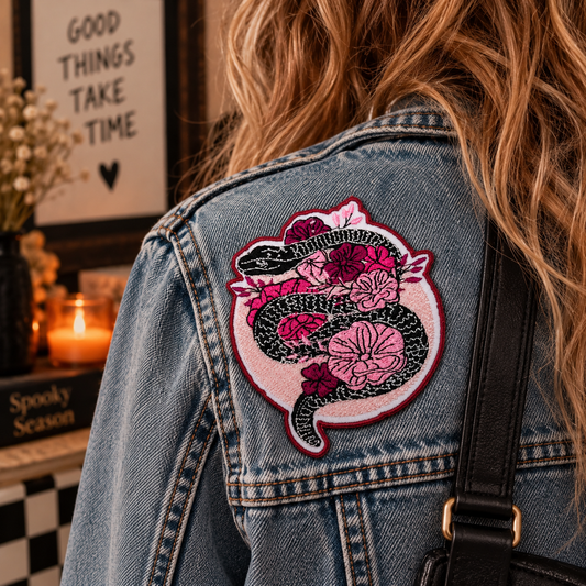 Black snake and pink flowers embroidered patch worn on a denim jacket