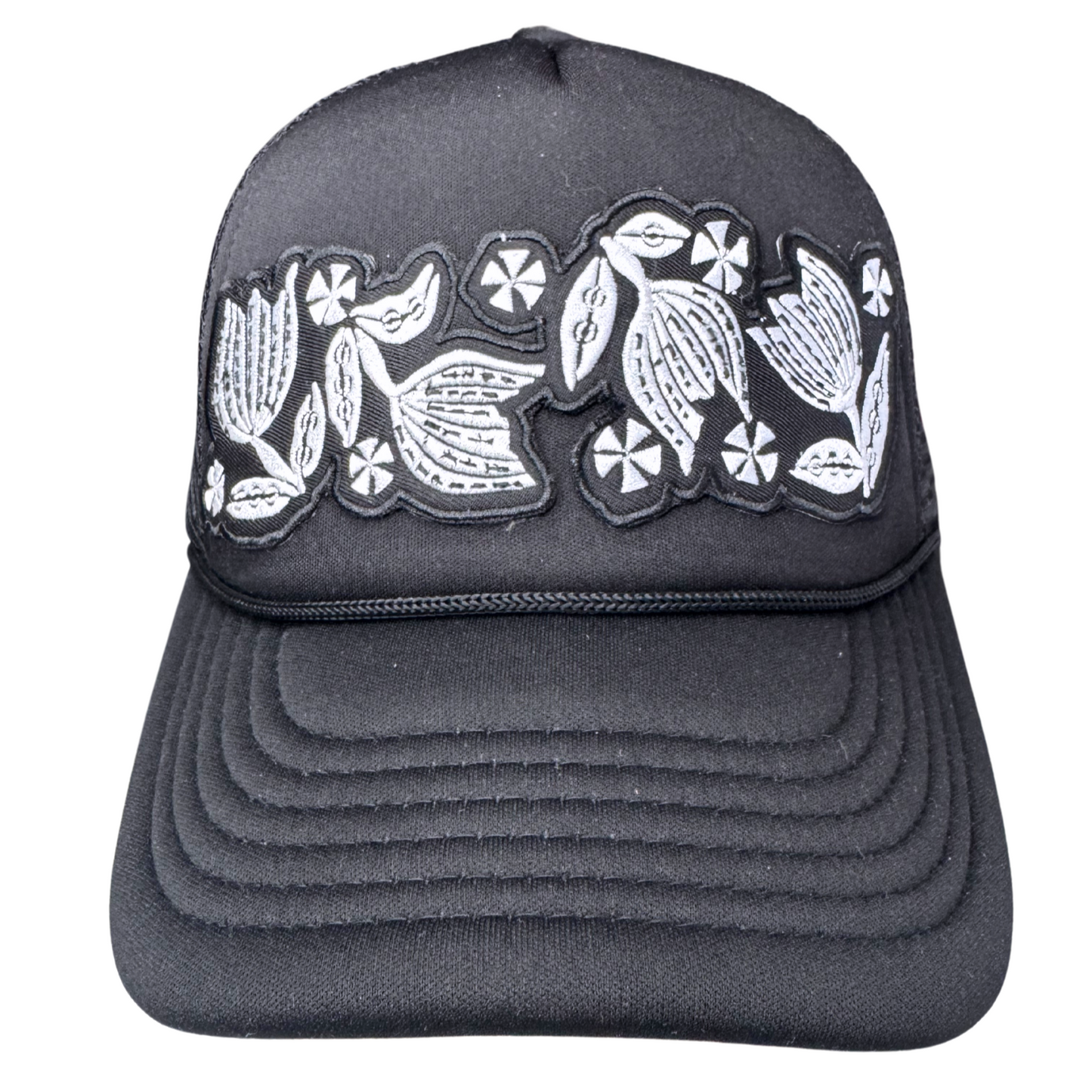 Front view of black trucker hat with black and white embroidered floral patch inspired by vintage Pyrex Black Tulip
