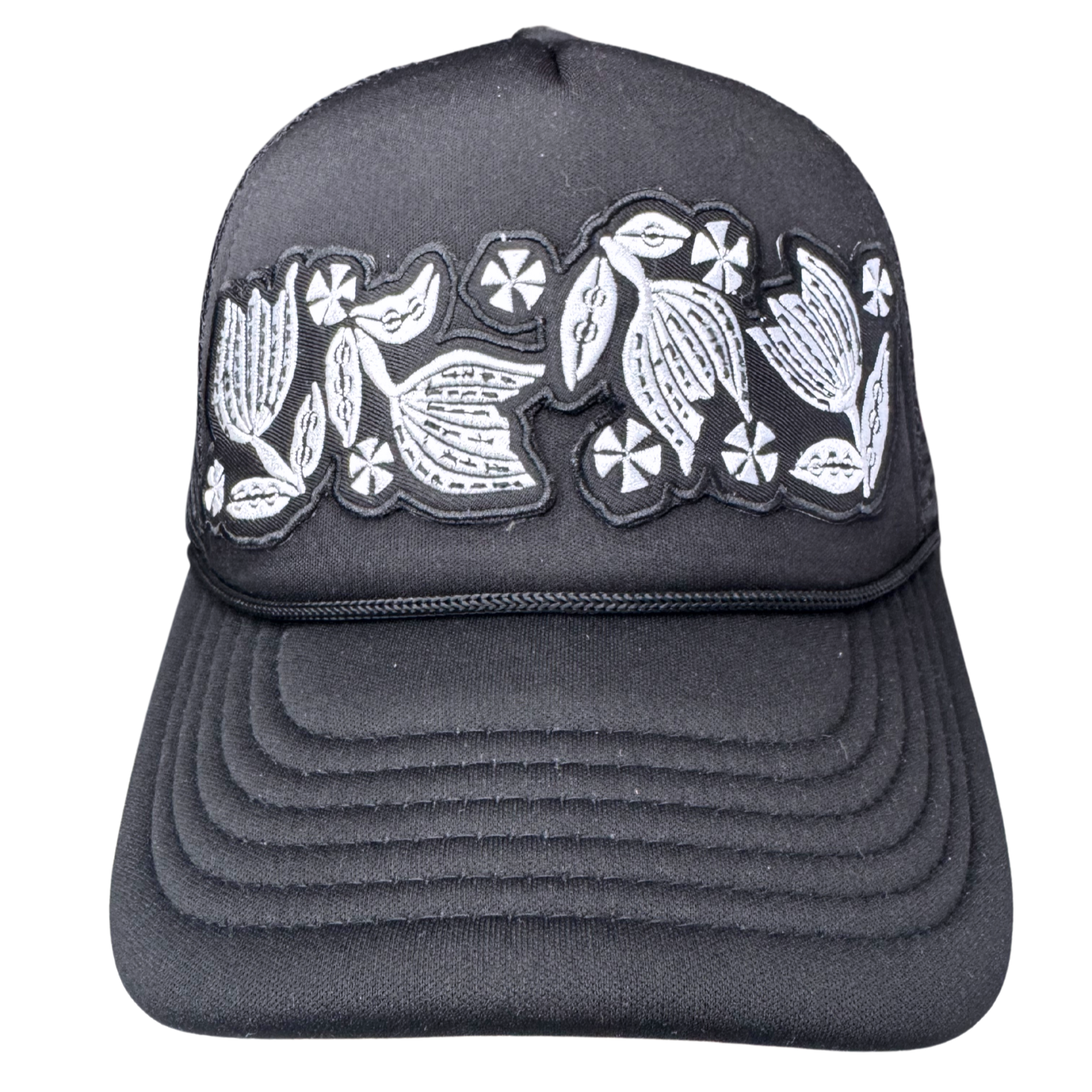 Front view of black trucker hat with black and white embroidered floral patch inspired by vintage Pyrex Black Tulip
