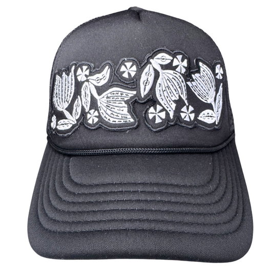 Front view of black trucker hat with black and white embroidered floral patch inspired by vintage Pyrex Black Tulip

