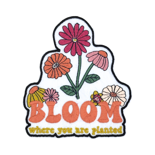 Close-up of an embroidered floral patch with the phrase "Bloom Where You Are Planted."
