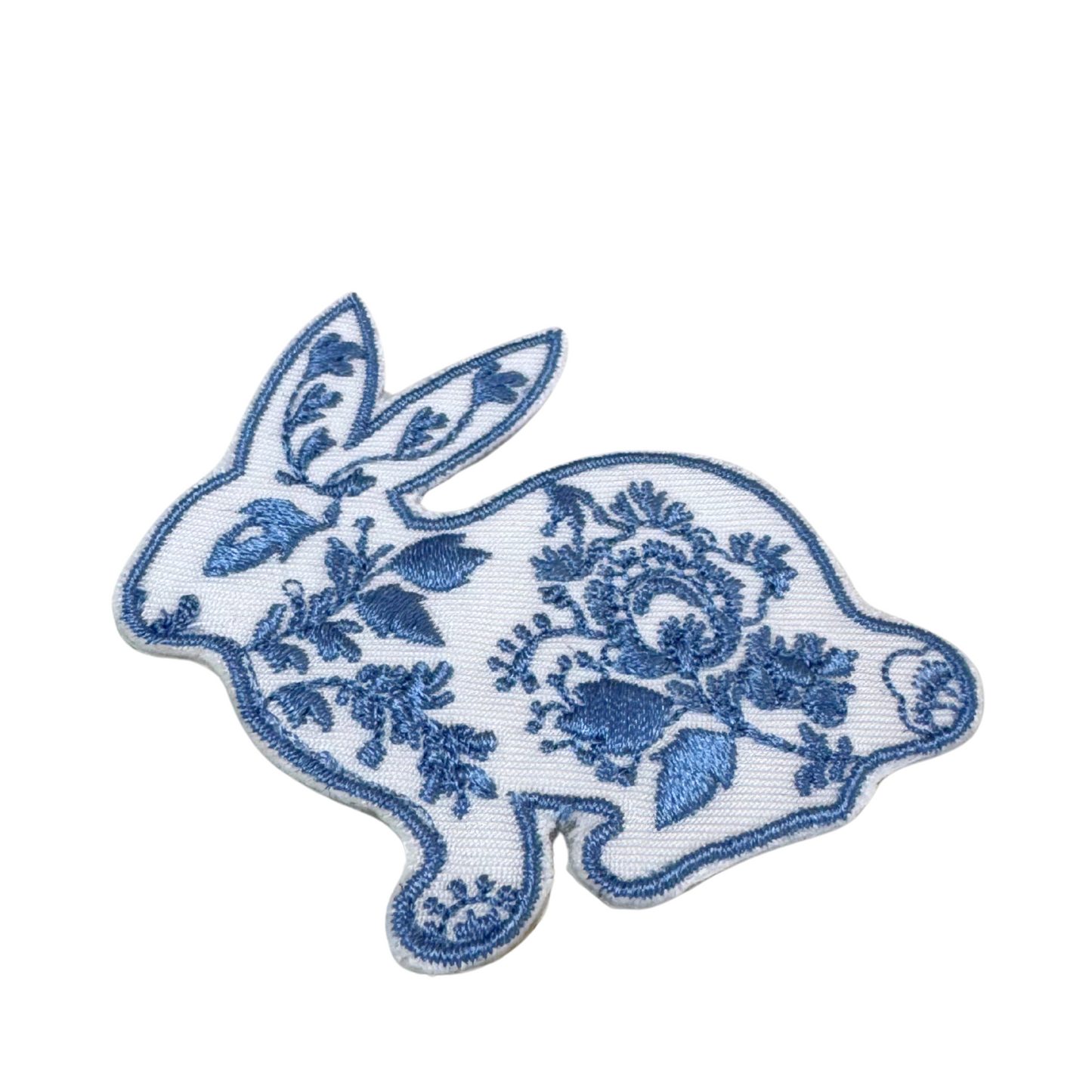 Close-up angled view of the blue and white floral bunny embroidery patch

