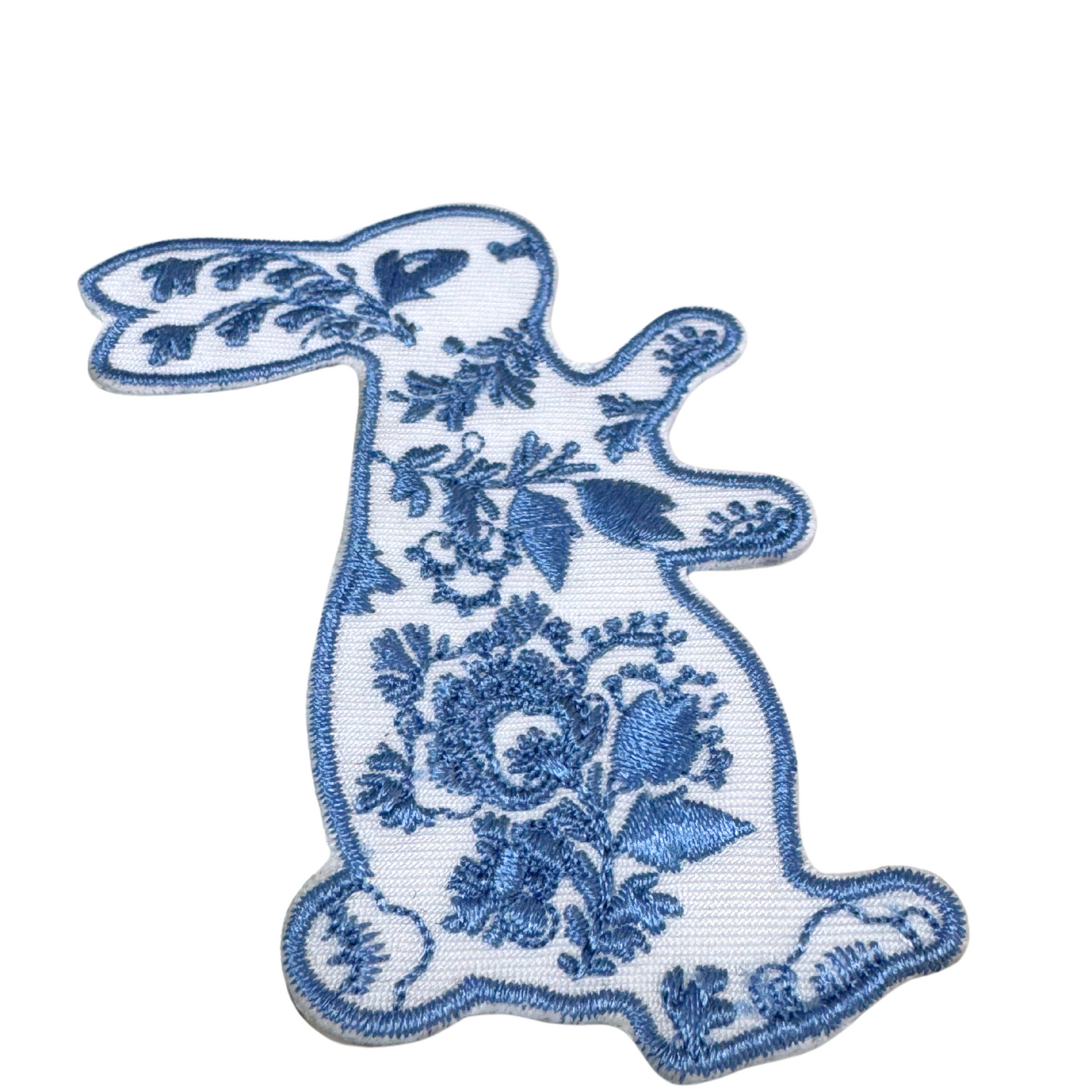 side angled close-up of embroidered floral bunny patch with blue floral details

