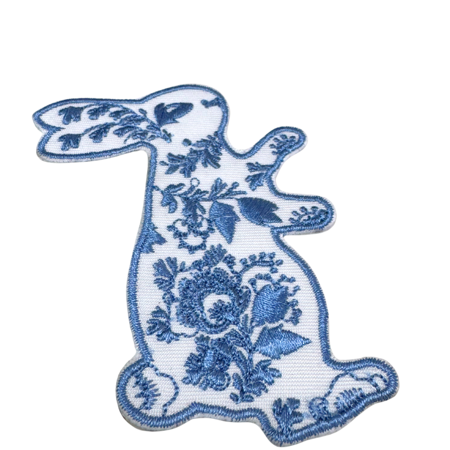 side angled close-up of embroidered floral bunny patch with blue floral details


