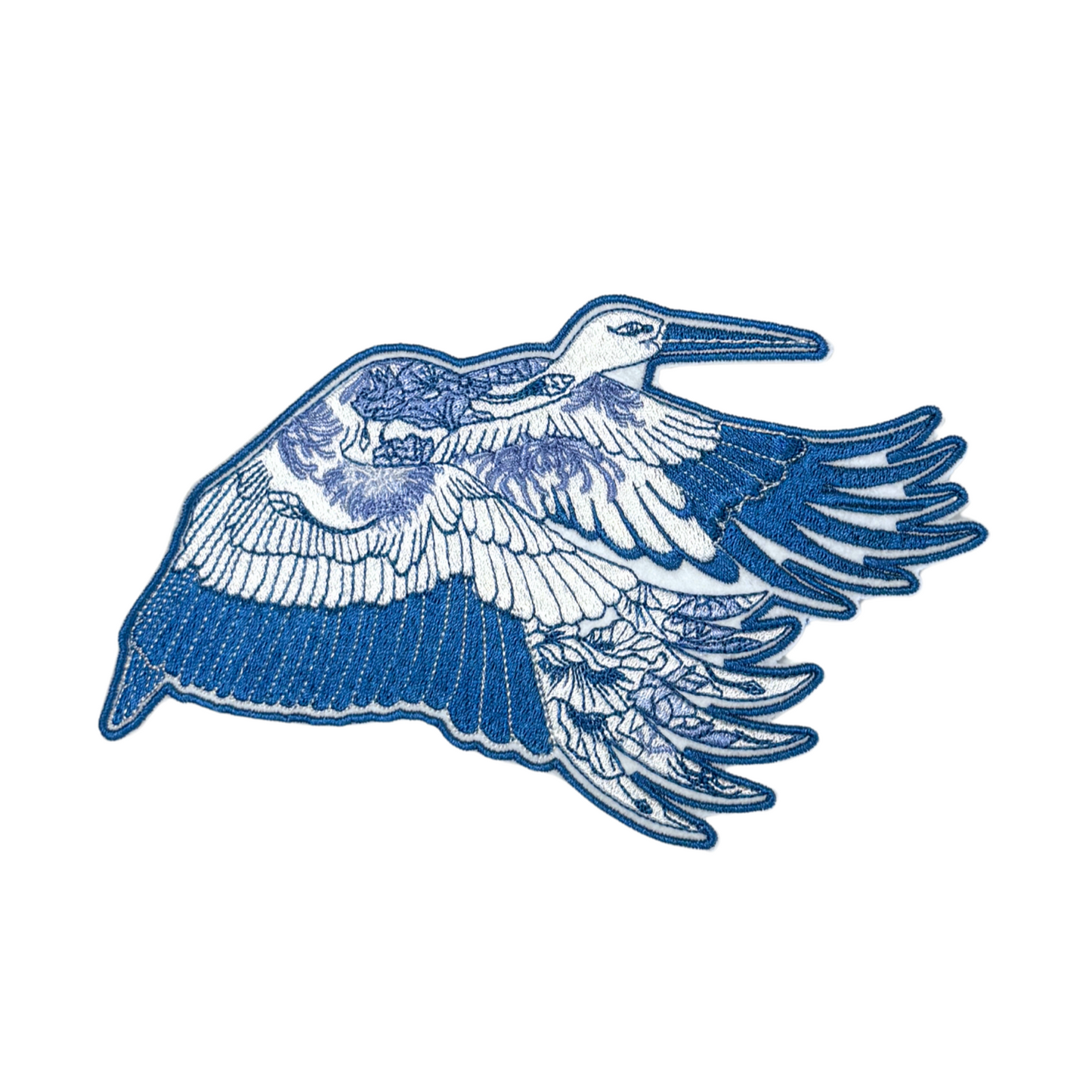 Close-up of a blue heron embroidered patch with intricate floral detailing.
