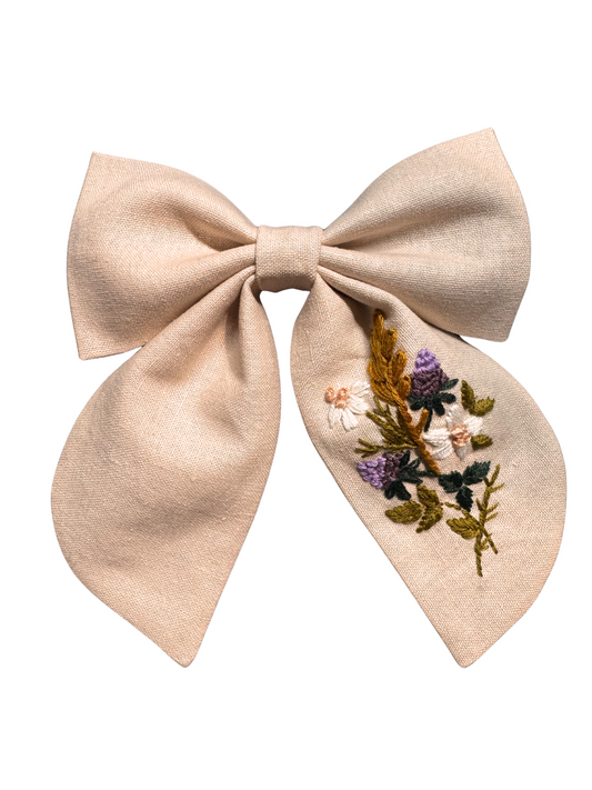 Blush linen bow with hand embroidered floral bouquet, attached to an alligator clip.