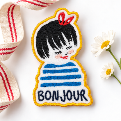 Bonjour Girl embroidered patch with black bob, red bow, blue stripes and golden yellow border