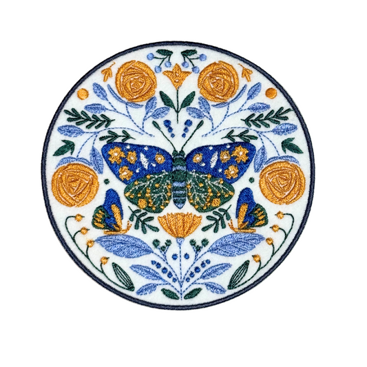 Symmetrical folk art-style butterfly embroidered patch with gold and blue flowers
